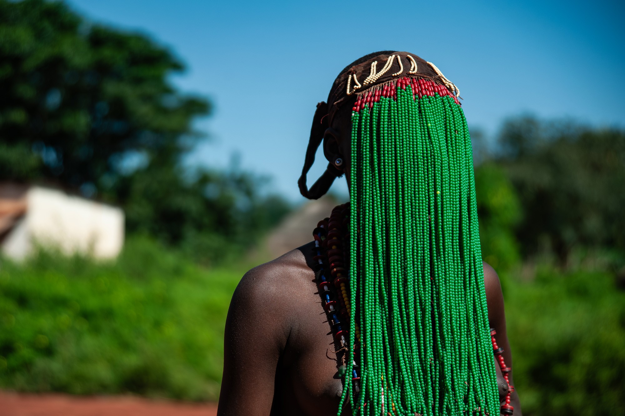 A girl wears a long veil made of green beads.