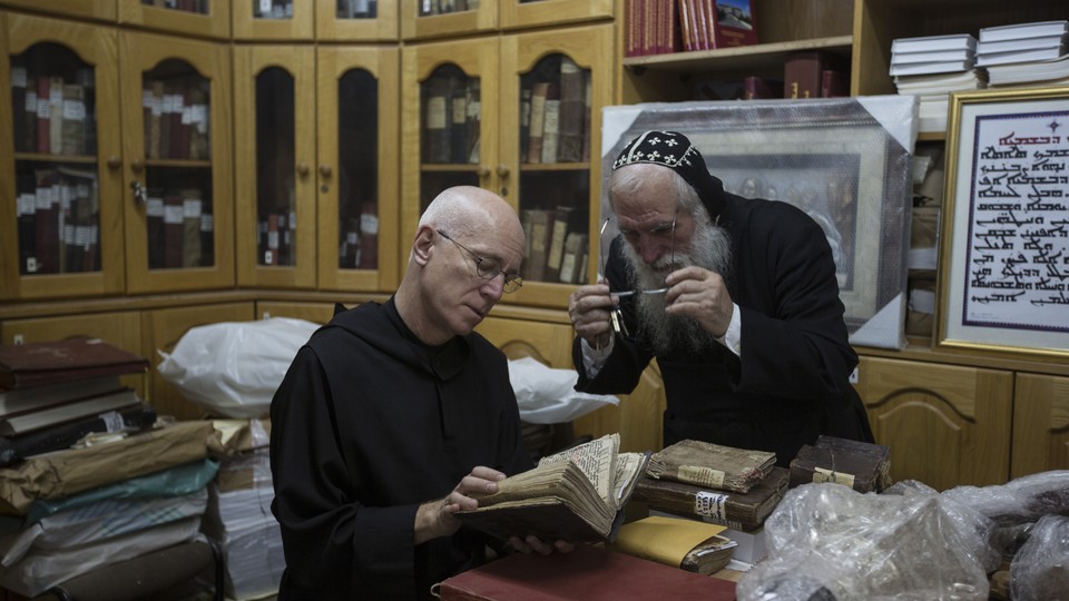 Father Columba Stewart inspects an ancient manuscript as a Syriac monk looks on at St. Mark’s Syrian Orthodox Monastery in Jerusalem.