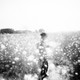 a black and white photo of a figure in a field of mustard plants