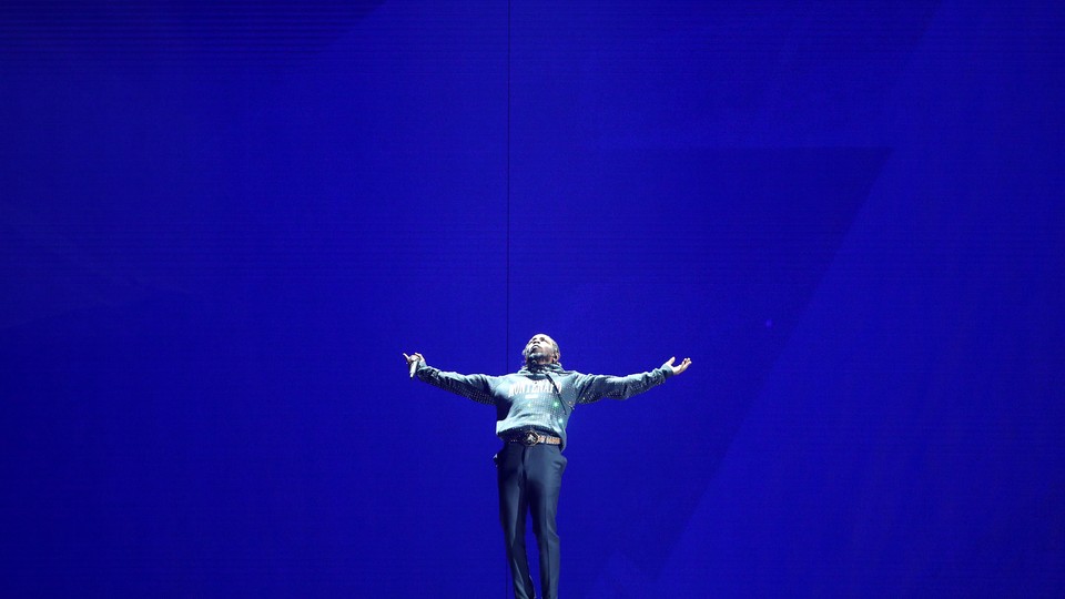Kendrick Lamar performing onstage against a blue backdrop