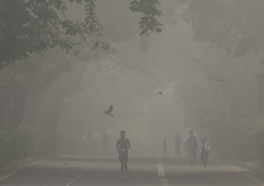 A man runs in a marathon while the sky is filled with smog.