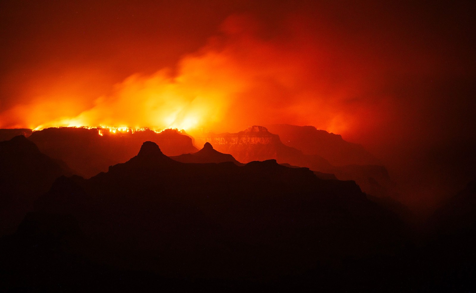 A night view of a wildfire burning along the rim of the Grand Canyon.