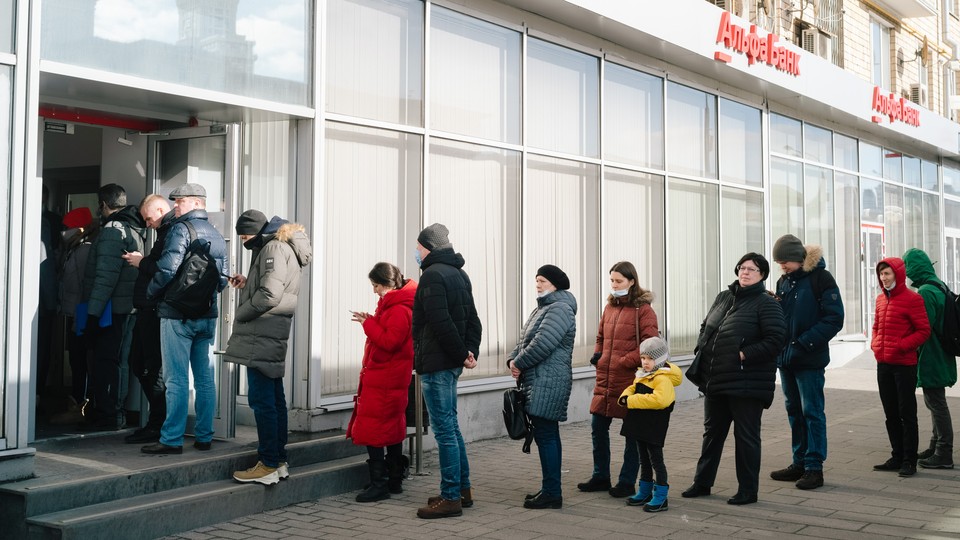 People stand in line to withdraw money from an ATM in Moscow, Russia.