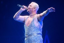 Sam Smith performing onstage in a glittering light-blue jumpsuit