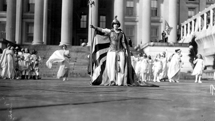 Suffrage pageant participants dressed in white stand in front of the Treasury Building, in Washington, D.C., on March 3, 1913.