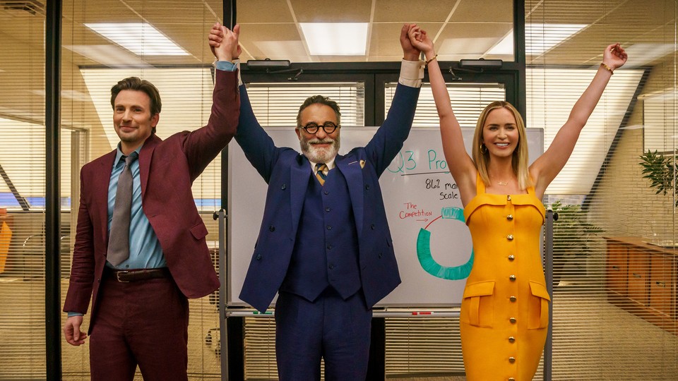 two men and one woman raising their arms in an office