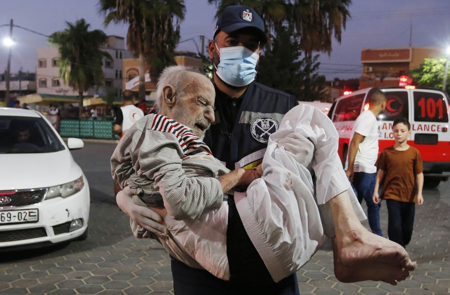An emergency worker carries an older man into a hospital.