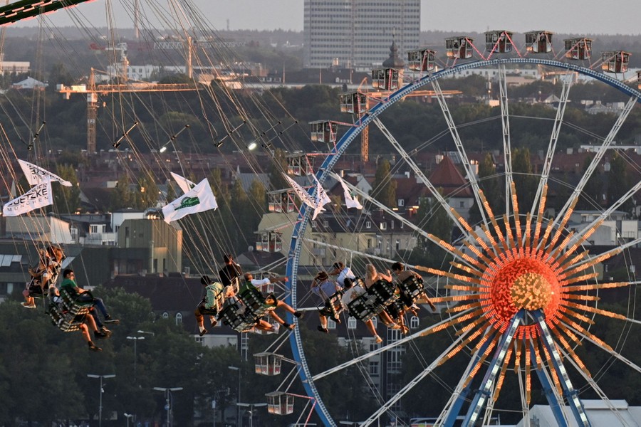 Festivalgoers ride on a tall swing carousel and a Ferris wheel.