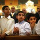 Five boys lean on a wooden pew at a Coptic Orthodox church.