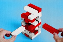 An illustration of a precarious Jenga tower with red and white blocks set against a blue background