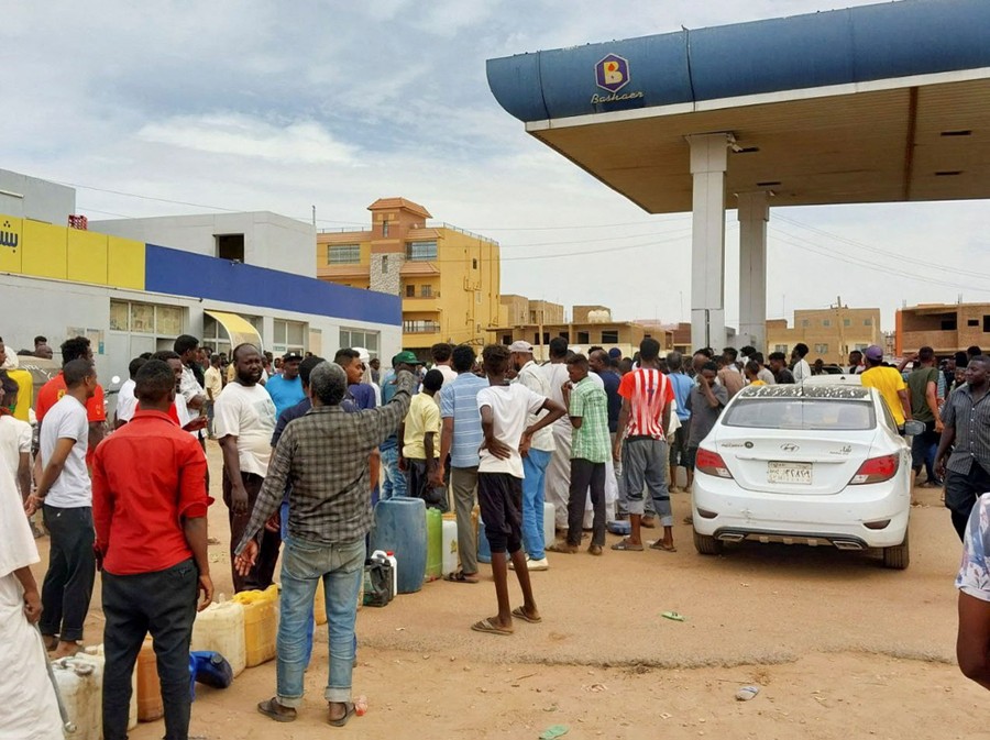 People stand in line to get fuel at a station.