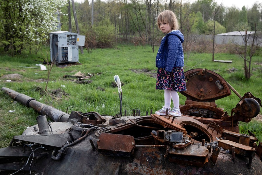 A child stands atop a destroyed Russian tank.
