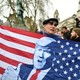 A man in London holds up a stylized American flag featuring Donald Trump