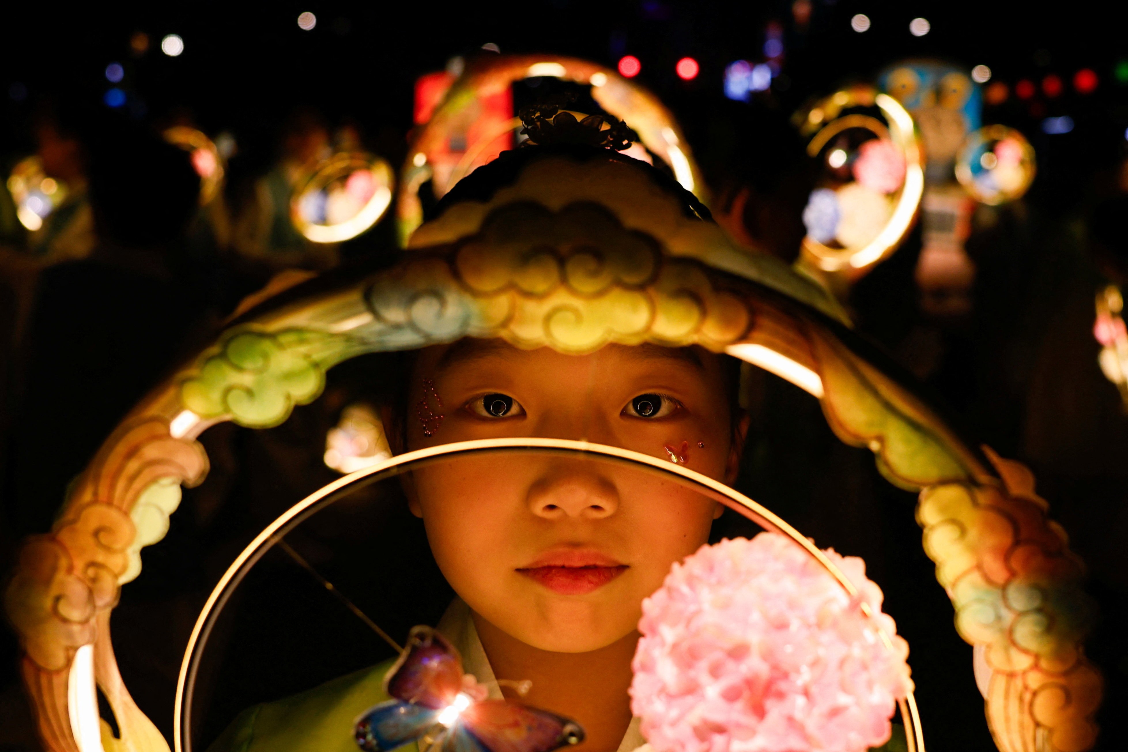 A girl carries a lantern in a parade.