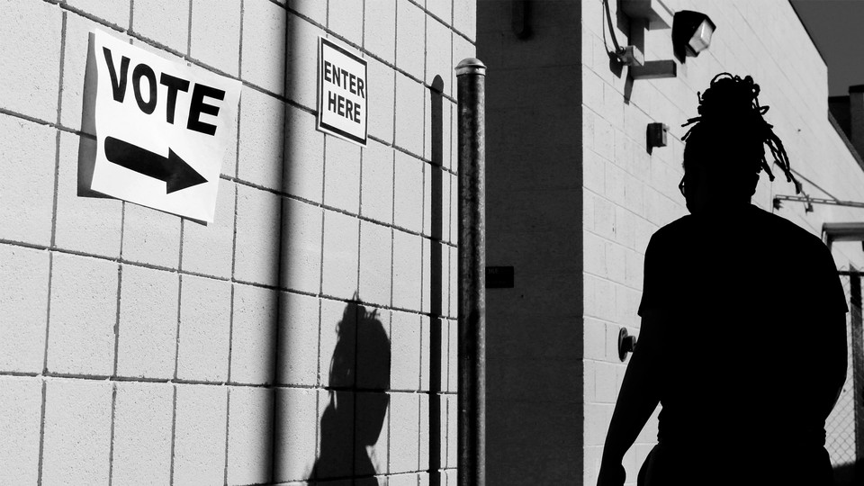 A person walking by a wall with a vote sign