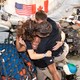 Four astronauts hug while inside a capsule, floating in micro-gravity.