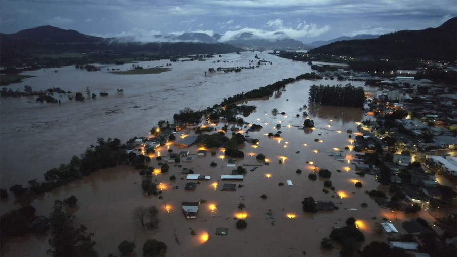 An aerial view of a flooded residential area, with some streetlights illuminating floodwater.