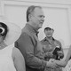 Black-and-white photo of Adam Schiff shaking hands with a person, surrounded by others