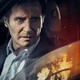 Liam Neeson in a car, looking at a fire outside