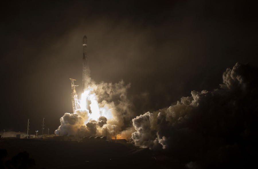 A rocket launches from a platform at night.