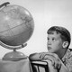 A young man stares at an old-fashioned globe