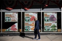 a man walks in front of posters advertising food