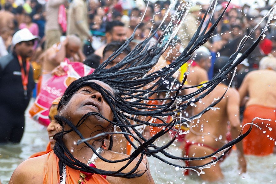 A woman tosses her wet hair back, flinging water into the air.