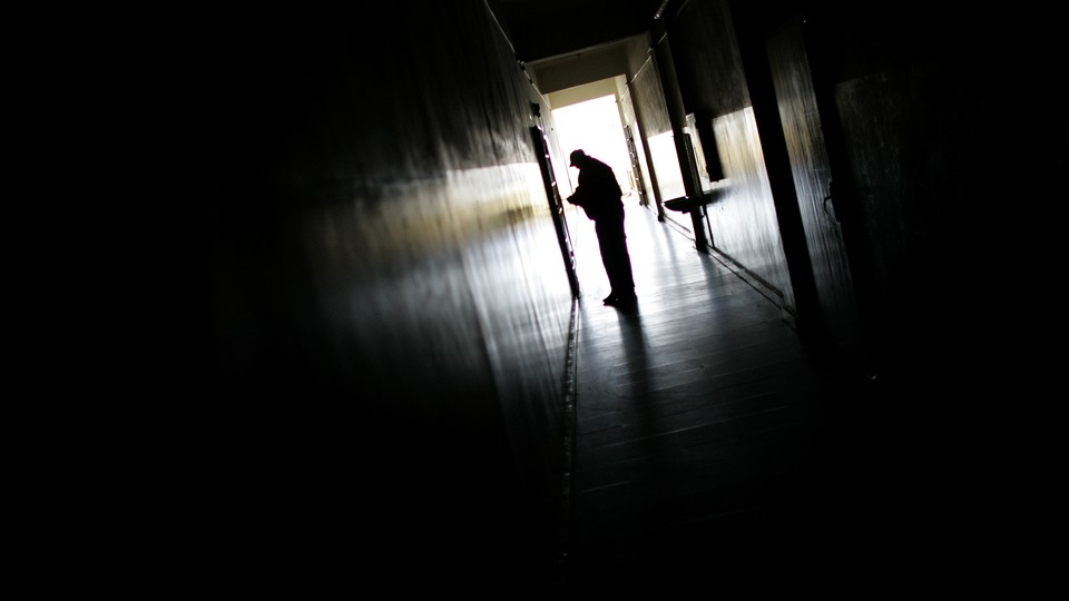 The silhouette of someone at the end of a dark hallway. 