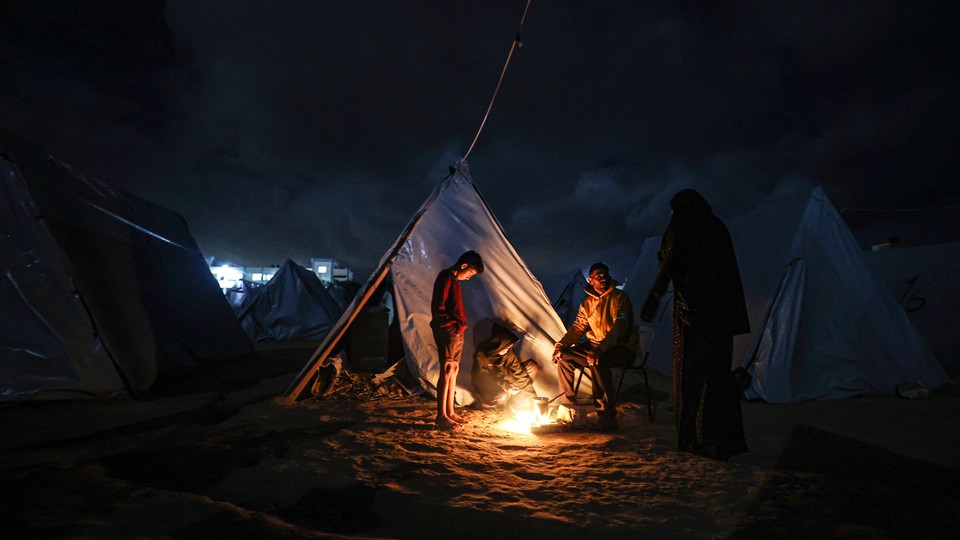 A family around a fire in a refugee camp
