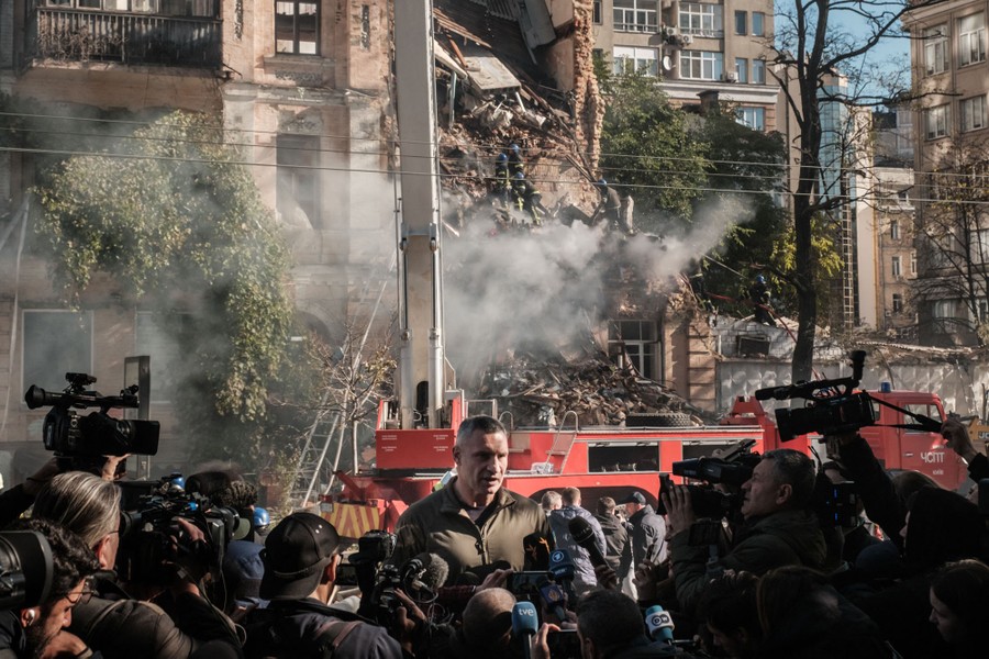 A tall man, the mayor of Kyiv, speaks to reporters outside a damaged building.