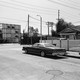 Black-and-white photo of a car at a stop sign and shipping containers across the street