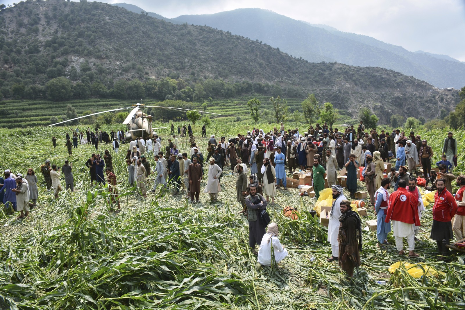 Afghan villagers gather around a military helicopter that landed in a field.