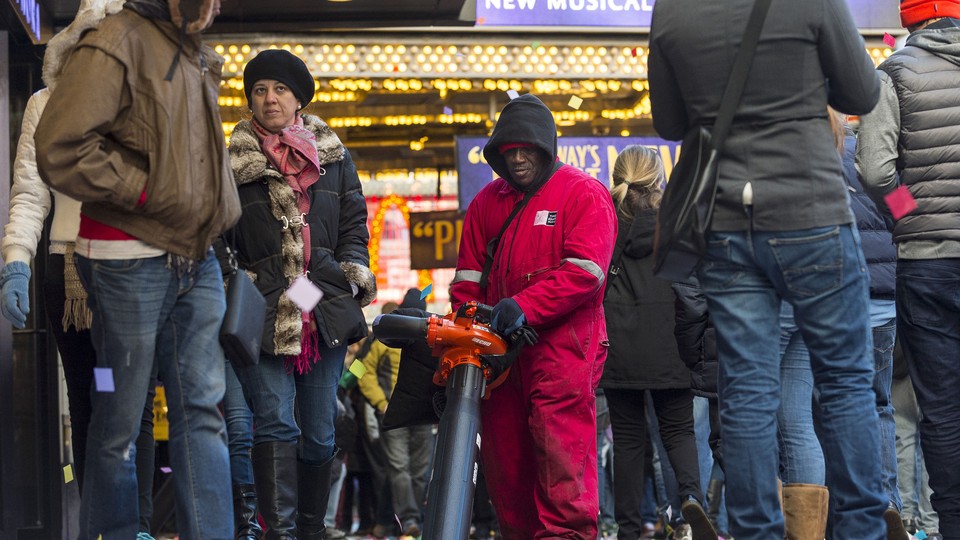 A man cleans up confetti while surrounded by tourists in Times Square in New York.