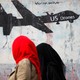 Women walk past a graffiti, denouncing strikes by U.S. drones in Yemen, painted on a wall in Sanaa, Yemen on February 6, 2017.