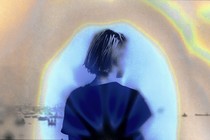 Image of a young woman from behind, surrounded by a hazy, colorful aura