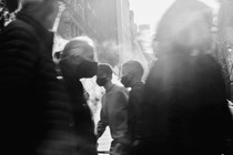 An American flag is seen through a crowd of people crossing the road on December 13, 2020 in New York City.