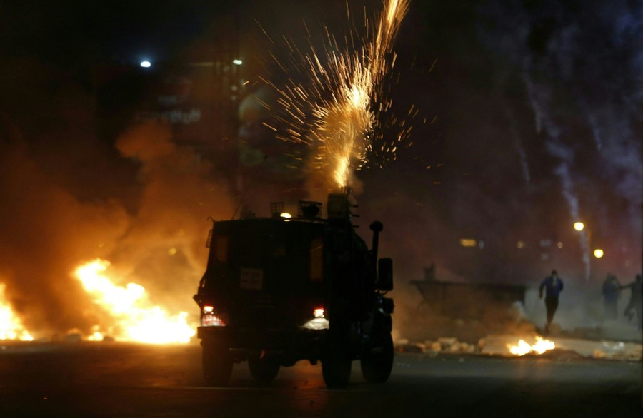 Sparks fly from a tear-gas launcher mounted on a police vehicle.