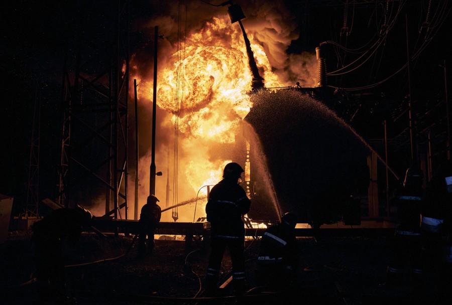 Firefighters battle a large fire at night.