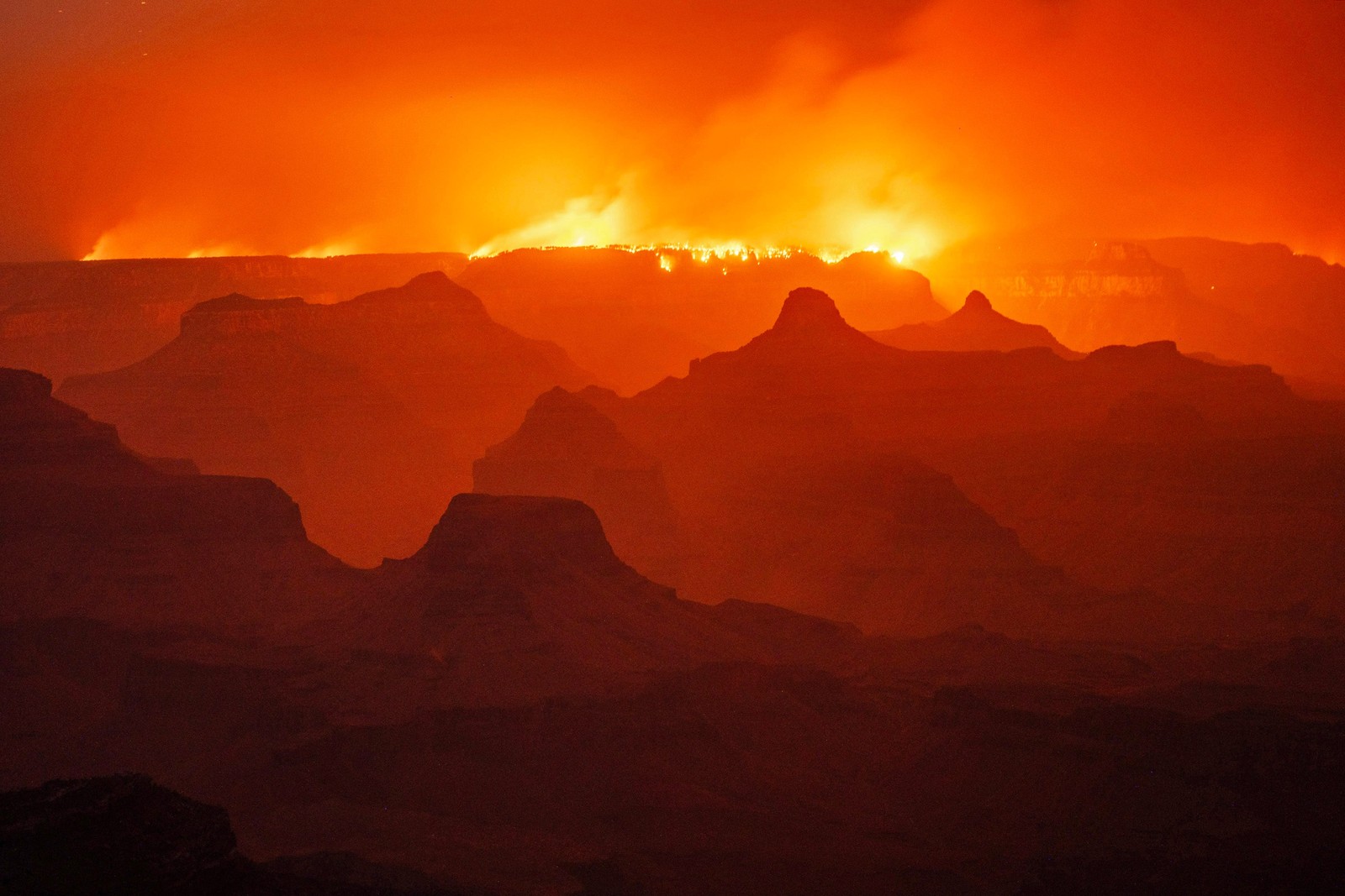 A night view of a smoky Grand Canyon, with a wildfire burning along the far rim