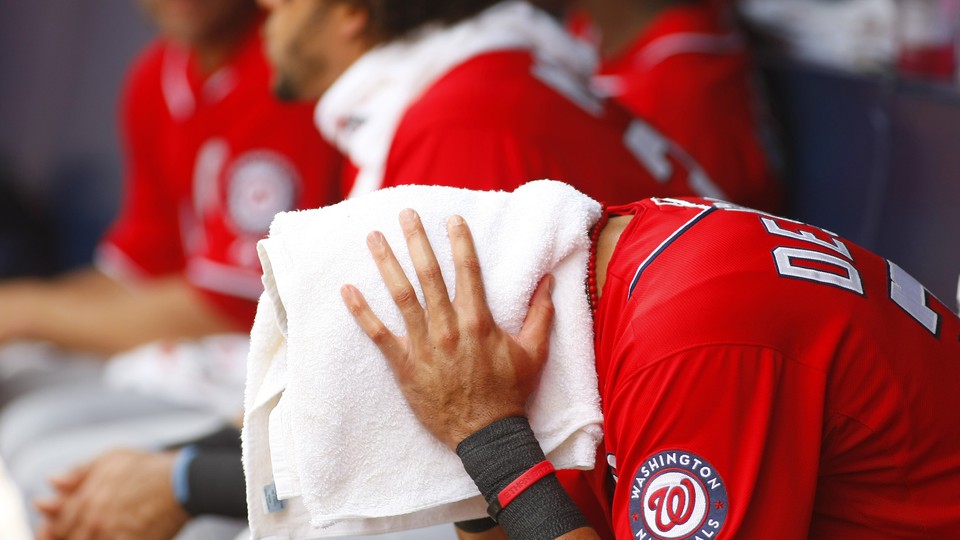 Washington Nationals shortstop Ian Desmond drapes a towel over his head to cool off in 100-degree heat.