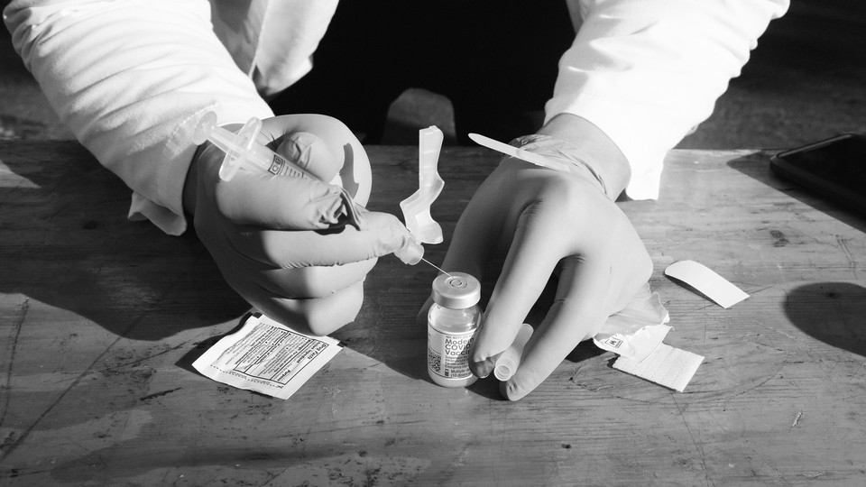 Photo of two gloved hands preparing a vaccine dose