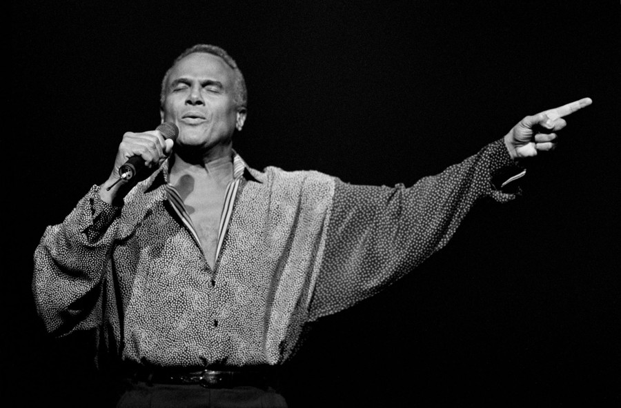 Harry Belafonte sings while gesturing on stage.