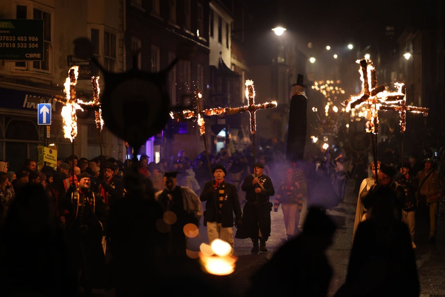 People march in a street, carrying effigies and burning crosses.
