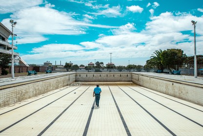 A man walks along the bottom of an empty public swimming pool near Cape Town.