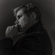 A black-and-white profile portrait of the writer Daniel Kehlmann in Berlin, his hand raised to his chin.