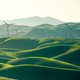 Wind turbines spin over a Elysian landscape of green fields