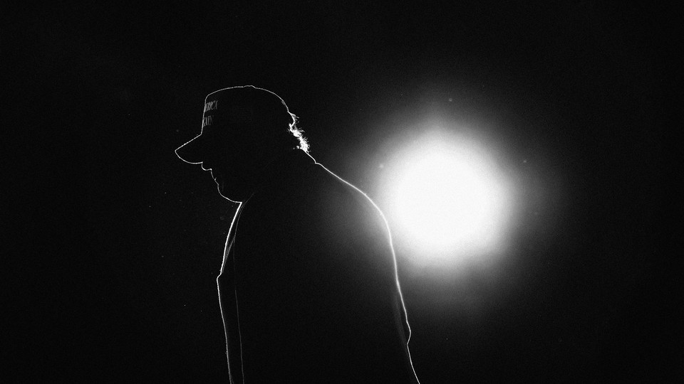 Donald Trump in silhouette, backlit by a single circle of light