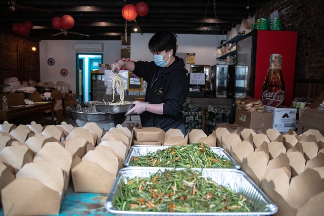 A chef filling takeout boxes.