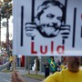 People celebrate and hold up a sign of former president Lula da Silva behind bars.