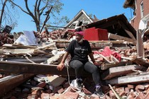 A woman sits on the wreckage of her home caused by a tornado in St. Louis, Missouri, May 18, 2025
